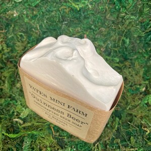 May include: A white bar of "Guinness Beer" soap from Yates Mini Farm, in a brown paper wrapper. The soap has a textured, foamy top. The label reads "Handcrafted Beer Soap - All Natural - 4.0 oz."