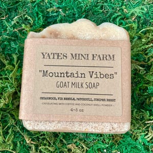 May include: A bar of goat milk soap with a brown paper label. The label reads "Yates Mini Farm" and "Mountain Vibes" with a list of ingredients and the weight of 4-5 oz.