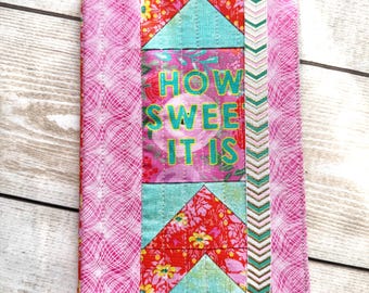 May include: A pink and turquoise fabric book cover with a chevron pattern and the text "HOW SWEET IT IS" in green letters.