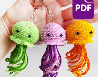May include: Three crocheted jellyfish keyrings in green, purple and orange. Each keyring has small black button eyes and a white ring for attaching keys.