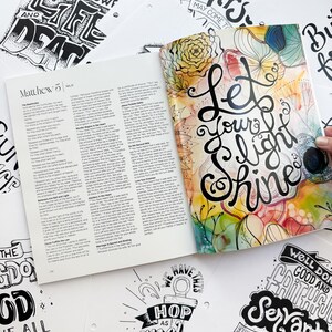 Pode incluir: Um livro aberto com texto de Mateus 5, rodeado por v&aacute;rias p&aacute;ginas brancas com cita&ccedil;&otilde;es inspiradoras manuscritas em preto e branco. A capa do livro apresenta as palavras "Let Your Light Shine" em escrita elegante com detalhes florais coloridos.