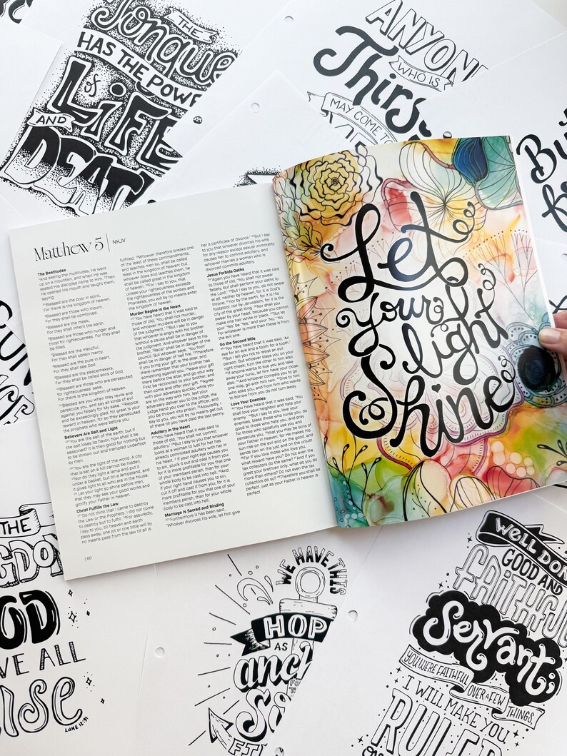 Pode incluir: Um livro aberto com texto de Mateus 5, rodeado por v&aacute;rias p&aacute;ginas brancas com cita&ccedil;&otilde;es inspiradoras manuscritas em preto e branco. A capa do livro apresenta as palavras "Let Your Light Shine" em escrita elegante com detalhes florais coloridos.