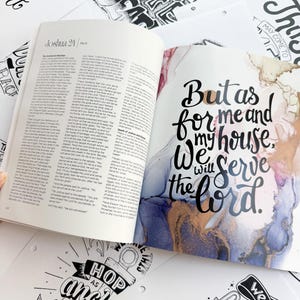 Pode incluir: Um livro aberto com o texto "Josu&eacute; 24" e uma p&aacute;gina com a cita&ccedil;&atilde;o "Mas eu e a minha casa serviremos ao Senhor" rodeada por arte abstrata em aquarela. V&aacute;rias impress&otilde;es de arte inspiradoras em preto e branco est&atilde;o espalhadas ao redor do livro.