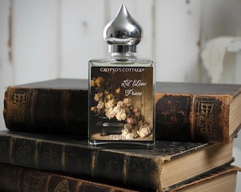 May include: A rectangular glass perfume bottle with a silver onion-shaped cap. The label features the text Calypso's Cottage and A Love Poem, accompanied by an illustration of a bouquet of pale roses in a dark vase against a muted background.