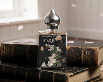 May include: A clear glass perfume bottle with a silver, onion-shaped cap. The label features the text Calypso's Cottage, Petals & Pages, and Perfume, set against a black background with an illustration of white and pink flowers and green leaves.
