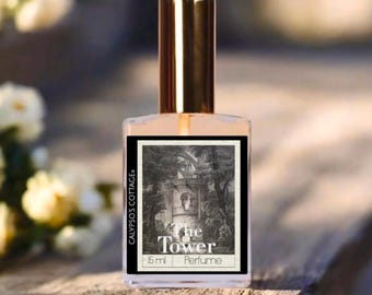 Può includere: Un flacone di profumo con tappo dorato ed etichetta con illustrazione in bianco e nero di una torre. L'etichetta include il testo "The Tower" e "Perfume". La bottiglia è etichettata "Calypso's Cottage" e contiene 15 ml di profumo.