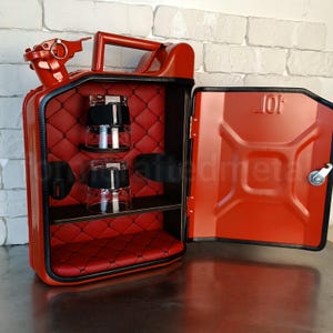 Pu&ograve; includere: Una tanica di metallo rossa trasformata in un mini bar. L'interno &egrave; rivestito in tessuto trapuntato rosso e presenta un ripiano e due bicchieri. La porta &egrave; aperta, rivelando l'interno. L'esterno ha una maniglia e un beccuccio.
