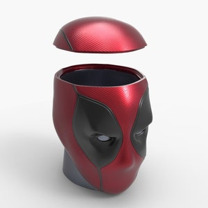 Może przedstawiać: Czerwono-czarny pojemnik w kształcie głowy Deadpoola z odpinaną pokrywką. Pojemnik jest wykonany z tworzywa sztucznego i ma fakturowaną powierzchnię.