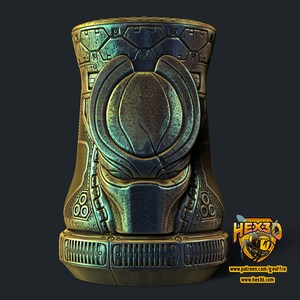 May include: A metallic, cylindrical sculpture with intricate, engraved details. The design features a stylized face and geometric patterns, with a color palette of bronze, teal, and gold. The base has a series of horizontal vents. The logo "HEX3D" is visible.