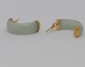May include: A pair of jade hoop earrings with gold accents. The earrings are a light green color and have a smooth, polished finish.