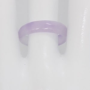 K&ouml;nnte beinhalten: Ein schlichter, helllila Ring aus glattem, poliertem Material. Der Ring wird auf einer wei&szlig;en Mannequin-Hand gezeigt.