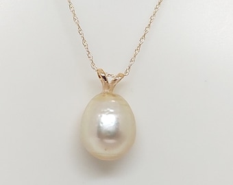 May include: A gold chain necklace with a single, large, white pearl pendant.