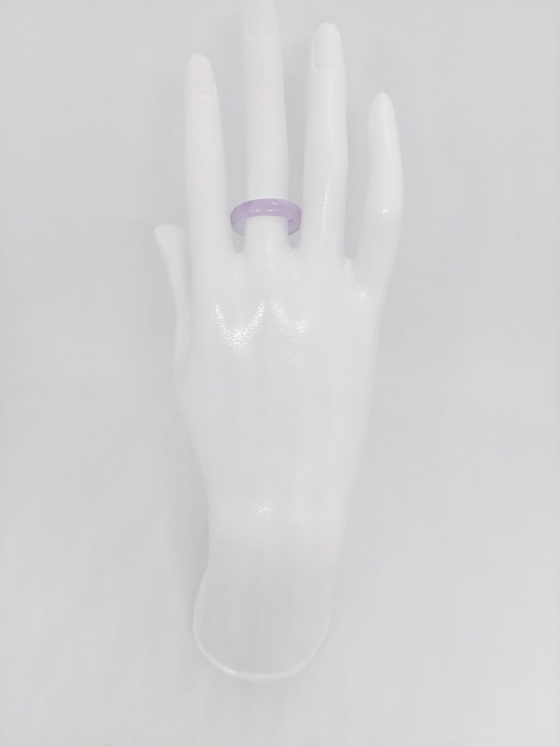 K&ouml;nnte beinhalten: Ein Ring aus Jade in Lavendelfarbe. Der Ring befindet sich an einer wei&szlig;en Mannequin-Hand.