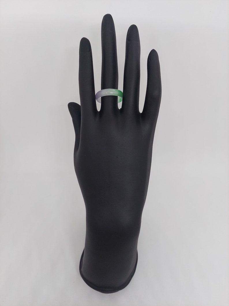 K&ouml;nnte beinhalten: Ein einfacher Jade-Ring mit einem gr&uuml;n-violetten Farbverlauf. Der Ring befindet sich an einem schwarzen Handmodell.