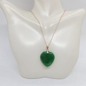May include: A gold chain necklace with a green jade heart pendant.