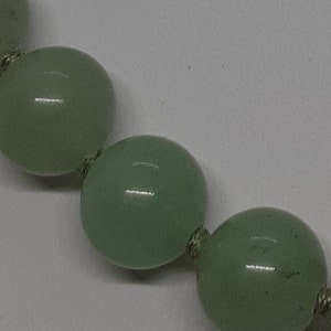 May include: A strand of light green jade beads with a knotted string.