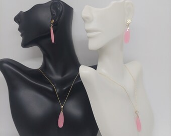 Puede incluir: Un conjunto de pendientes de gota de agua rosa y un collar colgante a juego. Las joyas están hechas de oro y presentan un diseño delicado.