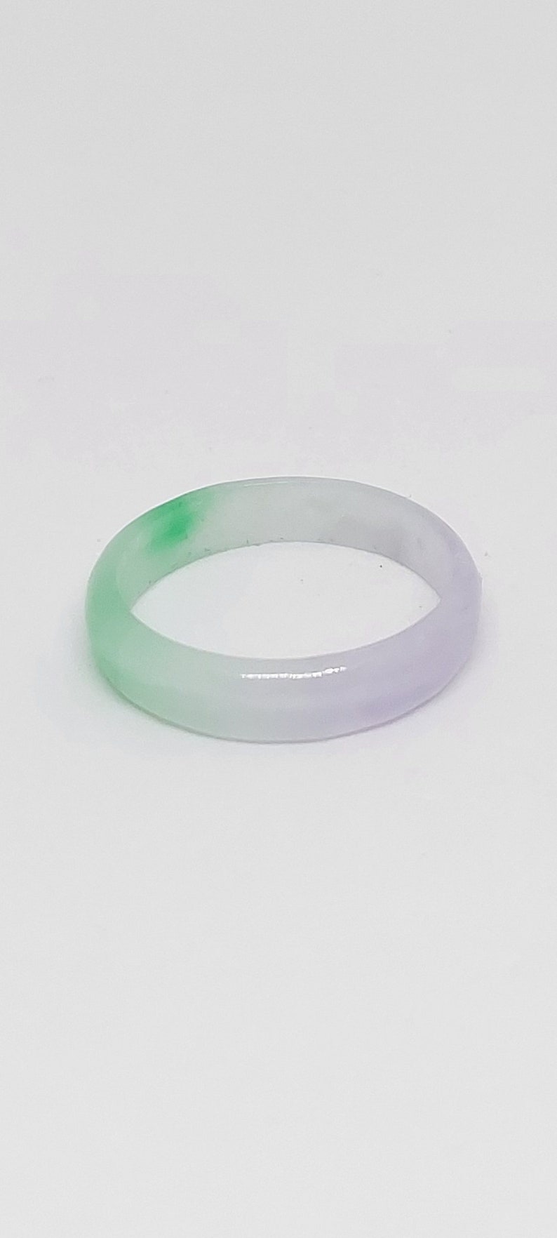 K&ouml;nnte beinhalten: Ein Ring aus hellgr&uuml;nem und wei&szlig;em Jade. Der Ring ist glatt und poliert.