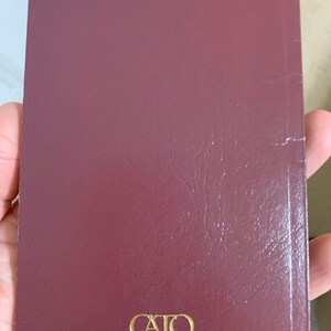 May include: A burgundy-colored book with the text "CAIO INSTITUTE" printed in gold on the cover.