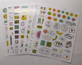 Pode incluir: Uma coleção de autocolantes coloridos para planeador com vários desenhos e texto. Os autocolantes incluem dias da semana, números, carinhas sorridentes e frases como "Faça", "Seja gentil" e "Objetivo".