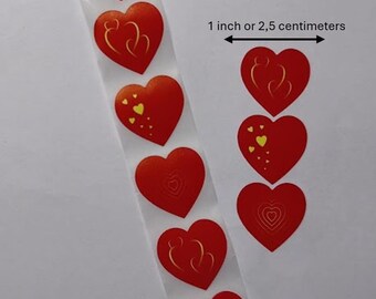 Könnte beinhalten: Ein Streifen roter herzförmiger Aufkleber mit goldenen und gelben Akzenten. Der Text auf dem Bild lautet "1 Zoll oder 2,5 Zentimeter". Die Aufkleber sind in einer vertikalen Linie angeordnet, ideal für Bastelarbeiten und Dekorationen.