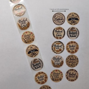 May include: A roll of round, brown stickers with the words "Baked with Love" in a decorative font. Each sticker features illustrations of baked goods like bread and croissants. The stickers are approximately 1 inch in diameter.