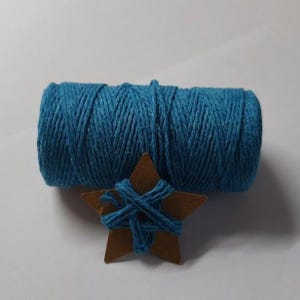 Peut inclure: Une bobine de ficelle bleu sarcelle est posée au-dessus d'une étoile en bois enveloppée de la même ficelle. La ficelle est bien enroulée et l'étoile est de couleur marron chaud. Idéal pour les projets d'artisanat.