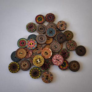 Pode incluir: Uma coleção de botões de madeira coloridos com padrões intrincados. Os botões são redondos e têm uma variedade de cores, incluindo vermelho, azul, verde, amarelo e laranja. Os botões estão dispostos em uma pilha, com alguns botões sobrepostos.