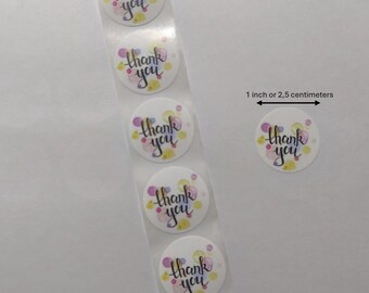 Può includere: Rotolo di adesivi rotondi da 2,5 cm con le parole "grazie" in scrittura nera su sfondo bianco con punti colorati ad acquerello.