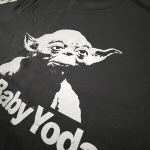 May include: Black t-shirt with a white graphic of Baby Yoda. The text "Baby Yoda" is printed in white below the image.
