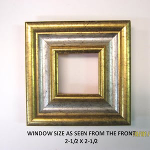 May include: Square picture frame with a gold and silver finish. The frame has a 2.5 x 2.5 inch window. The text on the image reads "WINDOW SIZE AS SEEN FROM THE FRONT 2-1/2 X 2-1/2".