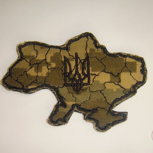 May include: A brown and green camouflage fabric patch shaped like the outline of Ukraine with a black embroidered trident in the center.