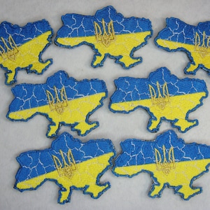 Può includere: Sei toppe ricamate a forma di Ucraina con i colori della bandiera ucraina, blu e giallo. Le toppe presentano lo stemma ucraino, un tridente, in oro.