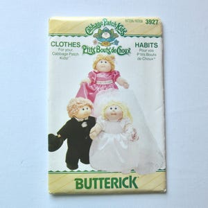 May include: A vintage Butterick pattern for Cabbage Patch Kids clothes and habits. The cover shows illustrations of Cabbage Patch Kids dolls in different outfits, including a pink dress and a wedding dress. The pattern number is 3927.