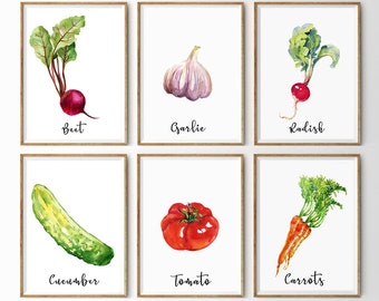 May include: Six framed watercolor prints featuring vegetables: beet, garlic, radish, cucumber, tomato, and carrots. Each print has a white background with the vegetable's name in a handwritten font below the image. The frames are a light brown color.