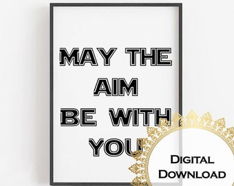 May include: Black framed print with the text "MAY THE AIM BE WITH YOU" in bold, black letters on a white background. A gold-colored circular design with the words "Digital Download" is in the lower right corner.