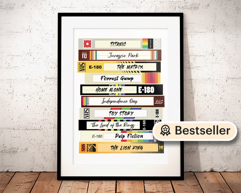 May include: A framed print of a stack of VHS tapes with movie titles like Titanic, Jurassic Park, The Matrix, Forrest Gump, Home Alone, Independence Day, Toy Story, The Lord of the Rings, Pulp Fiction, and The Lion King. The print has a "Bestseller" label.