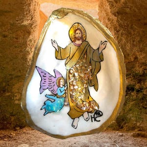 May include: An oyster shell art piece featuring a religious figure with a golden halo and robe, and an angel with purple wings. The artwork has gold accents and a signature in the lower right corner.