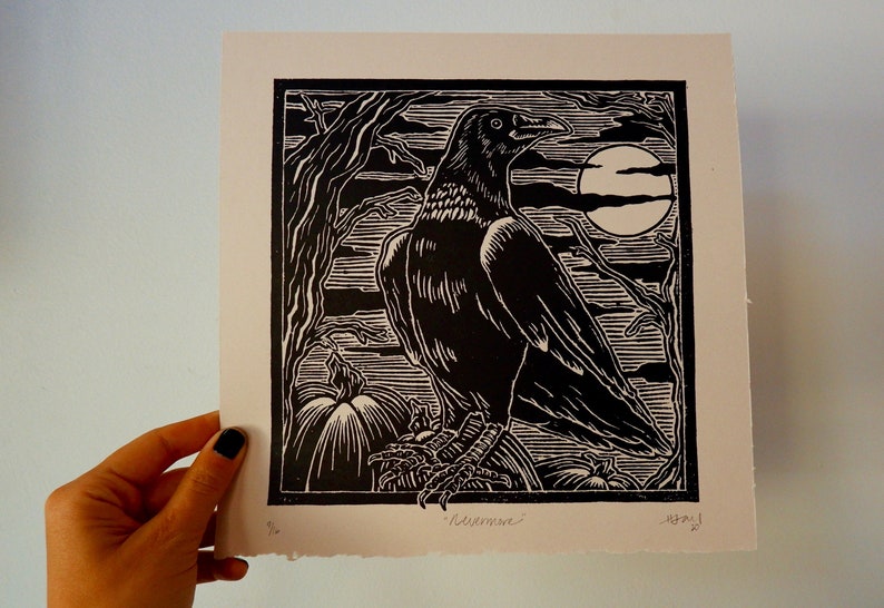 May include: Black and white woodcut print of a raven perched on a branch with pumpkins in the foreground. The raven is facing right and has a large beak. The moon is visible in the background. The print is signed "Redeemer" and dated "12/21".
