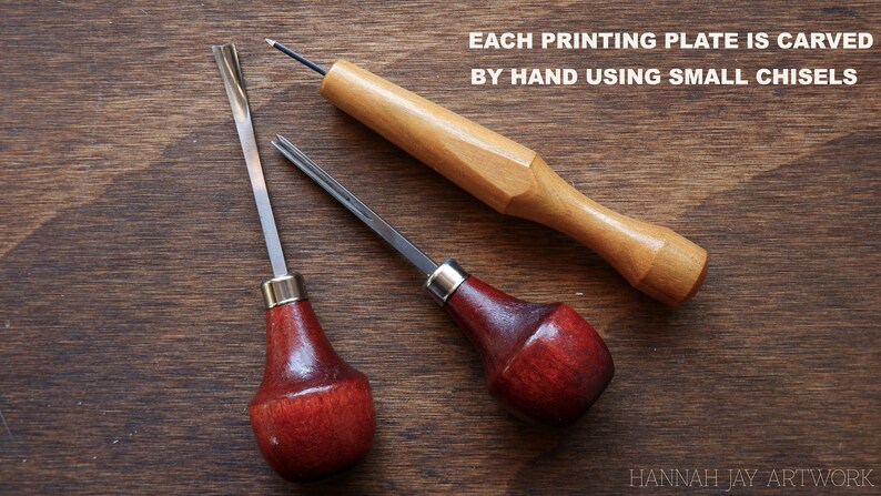 May include: Three wood carving tools with red and brown handles and metal blades. The tools are on a wooden surface. The text "EACH PRINTING PLATE IS CARVED BY HAND USING SMALL CHISELS" is above the tools. The text "HANNAH JAY ARTWORK" is below the tools.