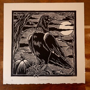 May include: Black and white woodcut print of a raven perched on a pumpkin with a full moon in the background. The print is signed "Livermore" and numbered 4/30.