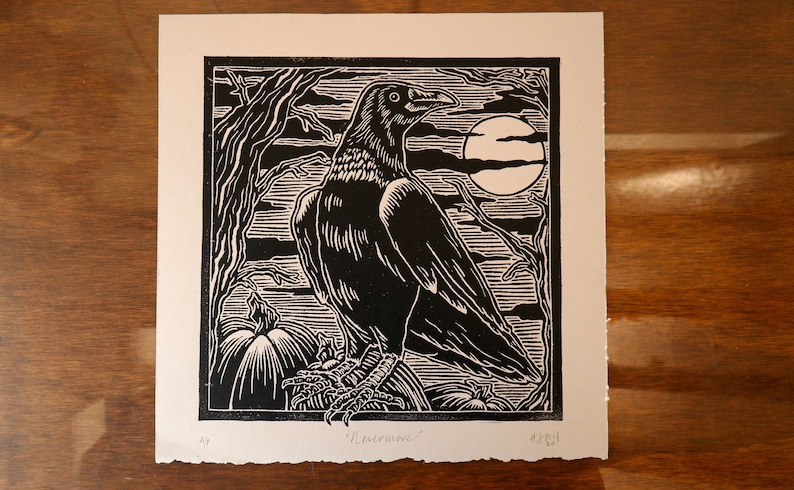 May include: Black and white woodcut print of a raven perched on a branch with pumpkins in the foreground and a full moon in the background. The print is titled "Ravenwood".