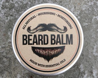 May include: A round metal tin with a brown label that says "All Natural Nourishing Moisturizing Beard Balm Made with Essential Oils". The label also features a black mustache and beard.