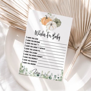 May include: A white card with the text "Wishes For Baby" and lines for writing. The card is decorated with watercolor pumpkins and greenery. The bottom of the card has the word "Love" and more greenery.