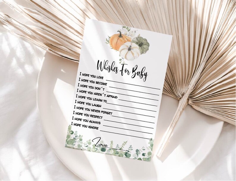 May include: A white card with the text "Wishes For Baby" and lines for writing. The card is decorated with watercolor pumpkins and greenery. The bottom of the card has the word "Love" and more greenery.