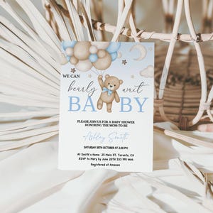 May include: Baby shower invitation with a teddy bear holding balloons. The invitation features the text "We can bearly wait BABY" in blue and brown colors. Additional text includes the date, time, and location of the baby shower.