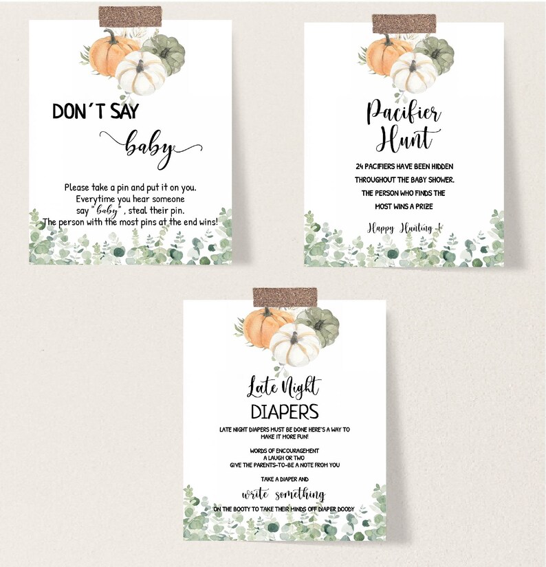 May include: Three baby shower game signs with watercolor pumpkins and greenery. The signs read "Don't Say Baby", "Pacifier Hunt", and "Late Night Diapers". Each sign is taped to the wall with decorative tape.