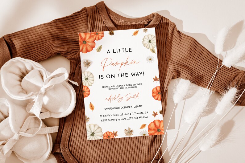 May include: A baby shower invitation with the text "A Little Pumpkin is on the Way!" features watercolor pumpkins, leaves, and daisies. The invitation is on a white background, with a brown onesie and baby booties.