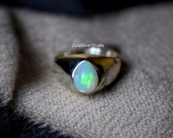 May include: A silver ring with a white opal gemstone. The ring has a simple, classic design.