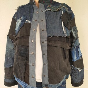 Puede incluir: Una chaqueta vaquera azul oscuro con un diseño de patchwork. La chaqueta está hecha de diferentes tonos de mezclilla azul y tiene un cierre de botones en la parte delantera.